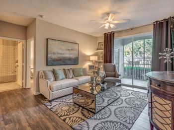 Furnished model living room area with sofa, coffee table and sliding doors leading out to patio